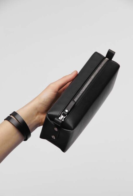 A hand holding a Big Dreamer Makeup Bag - Black case.