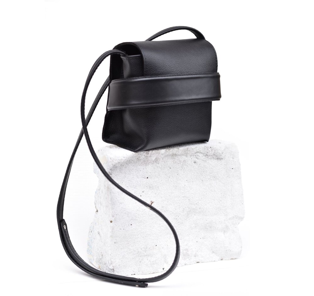 A Shoulder bag Luce - Black sitting on top of a rock.
