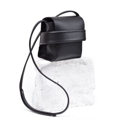 A Shoulder bag Luce - Black sitting on top of a rock.