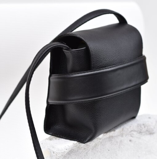 Un bolso bandolera de cuero negro con una correa.