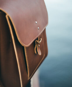Una mochila de cuero marrón sobre el hombro de una persona.