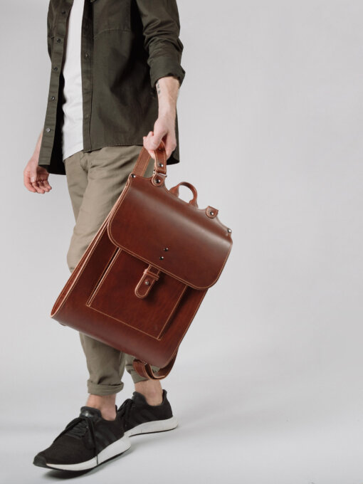 Un hombre que lleva una mochila de cuero marrón.